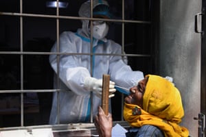 A health worker collects a swab sample from a resident to test for coronavirus at a testing center in New Delhi