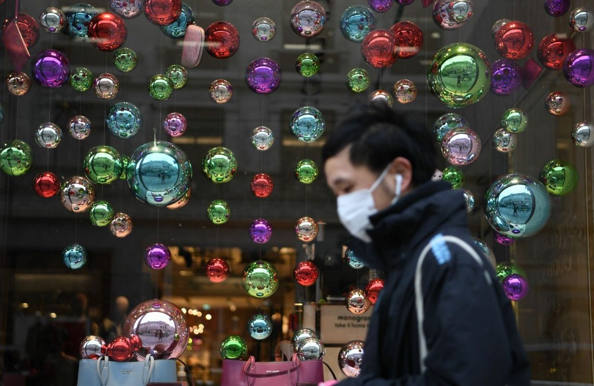 A man is seen walking past a festive window display in London during the pandemic