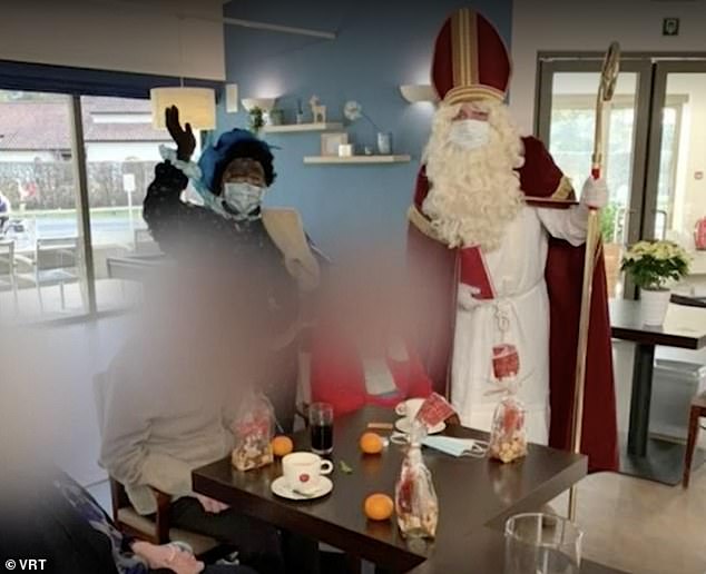 The volunteer dressed as Sinterklaas was welcomed to spread Christmas cheer among the 150 residents of the Hemilrejk nursing home in Mall, Antwerp, last week (Pictured: Residents enjoy wine and oranges as Santa and his aides Zwarte Piet ('Black Pete') visiting the house)